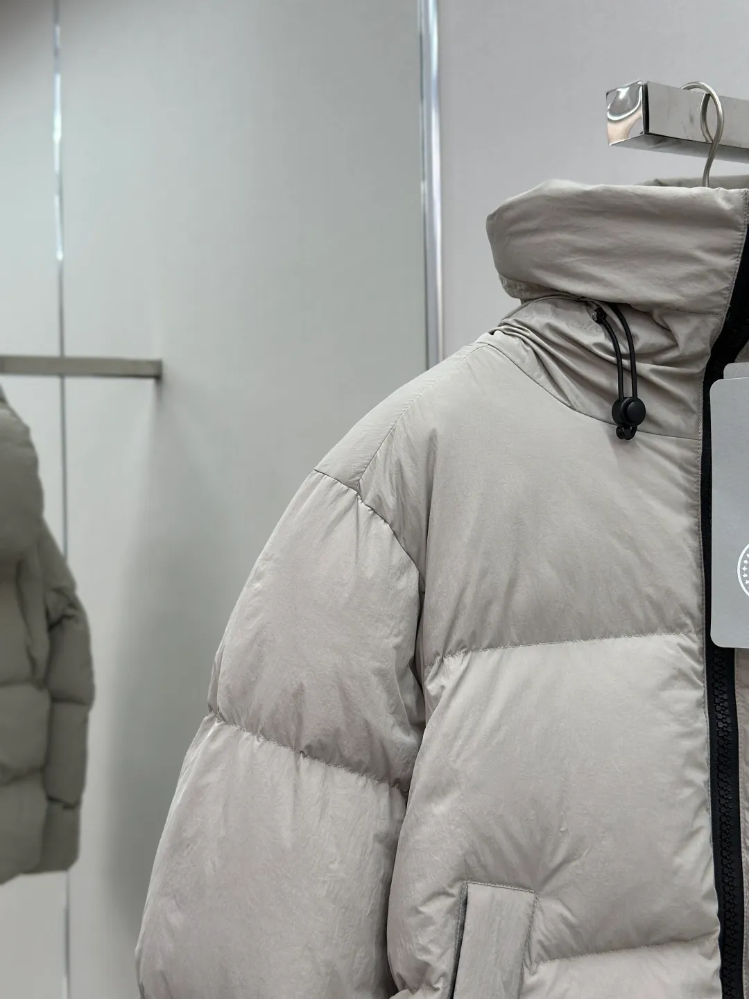 P1010 Canada Goose Black Label Badge Hooded Down Jacket (khaki) The high-quality filling is made of 90 national standard high-quality white duck down, selected high-loft velvet, weighing 240g, light and warm, with excellent temperature locking performance and good resilience. The fabric is woven with 400T high-count yarn. After special water-repellent treatment, the surface forms a lotus leaf effect - raindrops will slide down like beads, and snow particles will fall off when touched. The tear resistance reaches 200N (approximately 20kg load-bearing), the light gray matte texture breaks the stereotype of "outdoor clothing = hardcore", and the soft luster presents a high-end matte effect under urban neon lights, seamlessly switching scenes from ski resorts to CBD office buildings. The ribbon is woven with polyester as the base, and the brand letters are decorated on the ribbon through high-precision computer embroidery. The edges of the pattern are clear, the stitches are fine and even, and multiple layers of embroidery thread are stacked to enhance the three-dimensional effect. Precision thread reinforcement prevents linting and ensures the fluffy and resilient elasticity lasts as new. The embedded cuffs are three-dimensionally woven to form a "wavy" elastic structure, which forms natural folds when fitting the wrist, increasing the contact area with the skin, thus improving the windproof effect. At the same time, micro-velvet treatment is added to the inside of the cuffs, which feels like a second layer of skin and avoids friction on the skin from metal zippers or hard fabrics. Size:S-M-L-XL